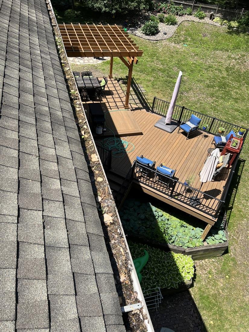 Gutter thick with built-up silt and debris above a backyard deck