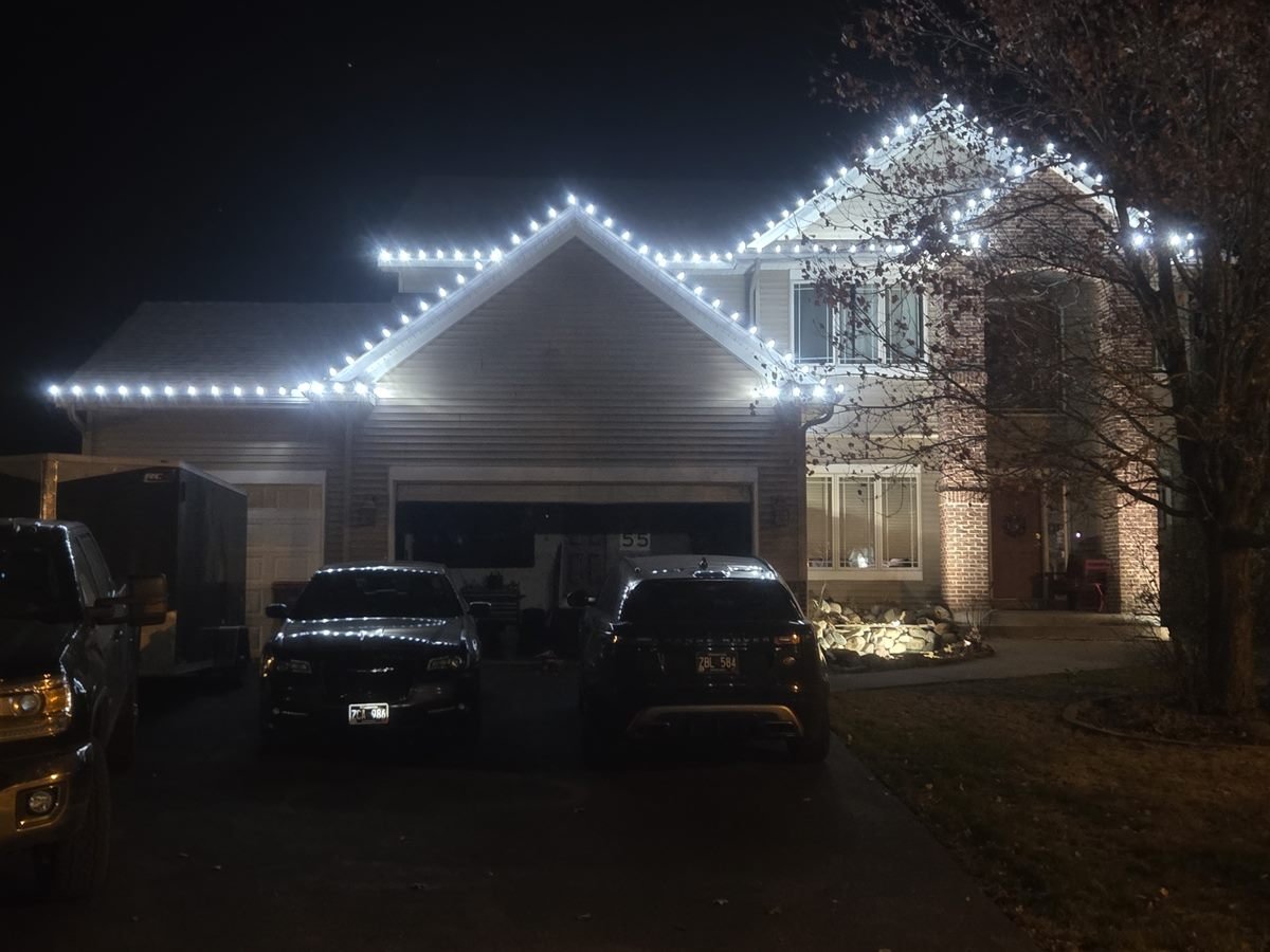 A two-storey home at night with white holiday lights running along every roofline, peak and gable